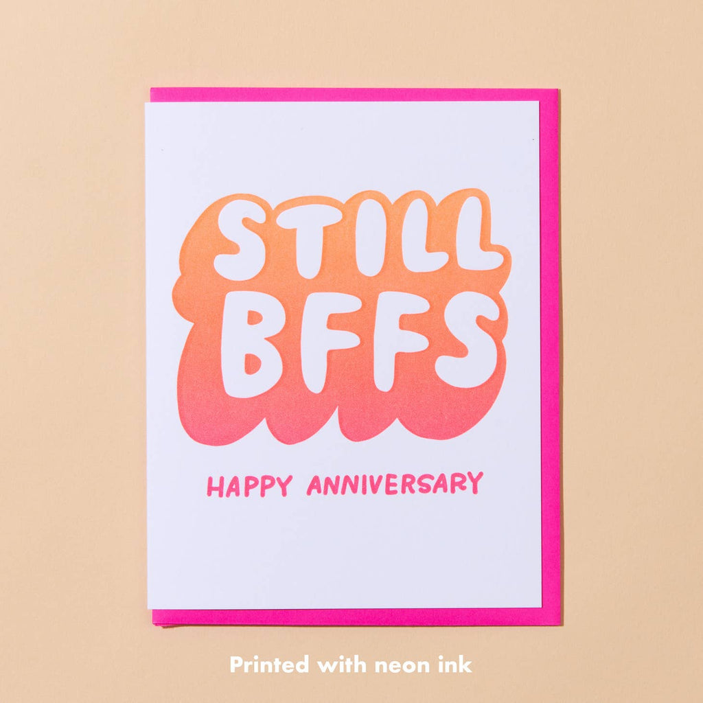 White card with orange ombre bubble text saying “Still BFFS” with “happy anniversary” in neon pink text. Neon pink envelope.      