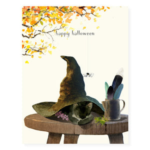 Ivory card with black text saying, "Happy Halloween". Images of a black witch's hat with a black cat sitting on a stool. An envelope is included.
