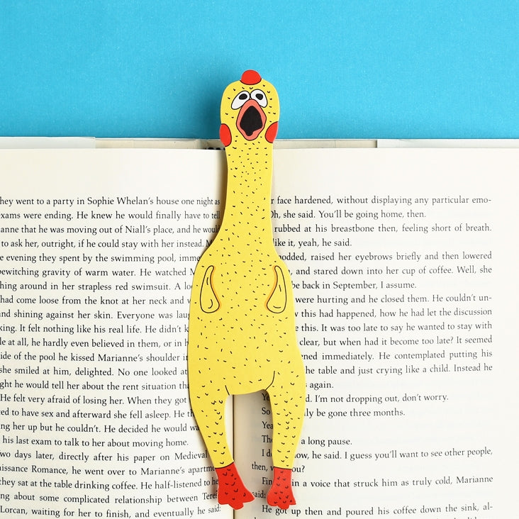 Image of opened book with an image of a yellow rubber chicken with red feet and crest with orange beak. 