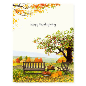 Ivory card with black text saying, "Happy Thanksgiving". Images of a fall scene of an apple tree with benches and pumpkins.  An envelope is included.