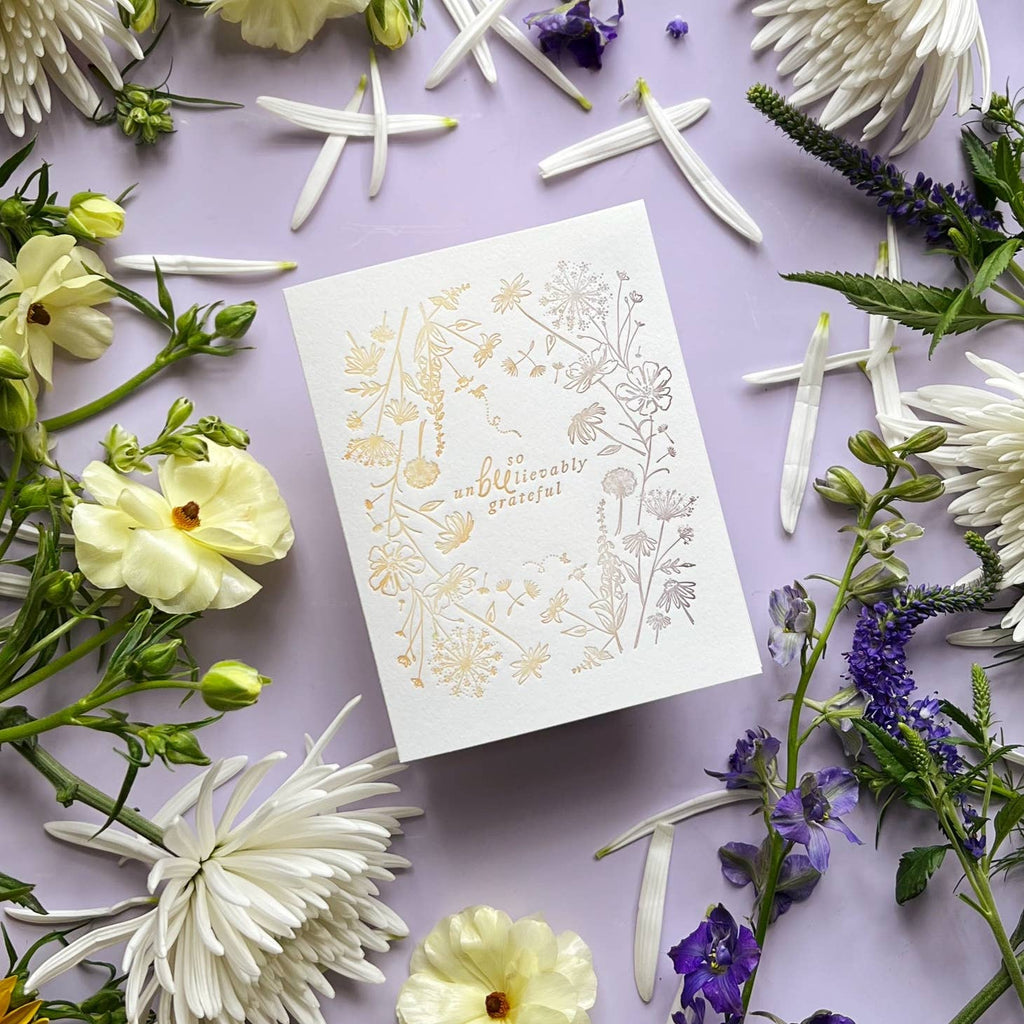 Ivory background with silver and gold flowers and tiny bees bordering the card with gold and silver text in the middle says, “So UnBEElievably grateful”. An envelope is included. 