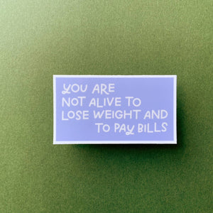 Lavender sticker with "You Are Not Alive To Lose Weight And To Pay Bills" in white lettering