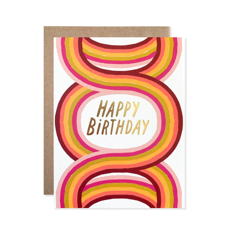 White card with gold foil text saying, “Happy Birthday”. Images of colorful arches. A brown envelope is included.