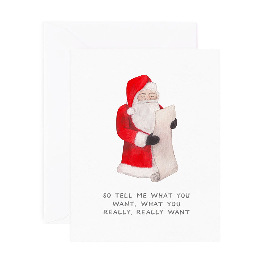 White card with black text saying, “So Tell Me What You Want, What You Really, Really Want”. Image of Santa Claus looking at list. A white envelope is included.