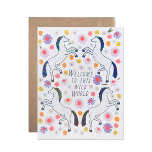 White card with black text saying, “Welcome to This Wild World”. Images of four horses surrounded by colorful daisy flowers. A brown envelope is included.