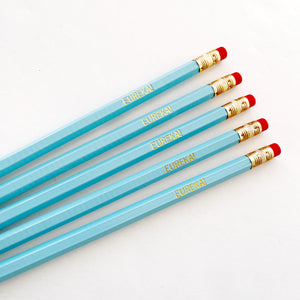 Image of blue pencils with gold foil text says, "Eureka!". 