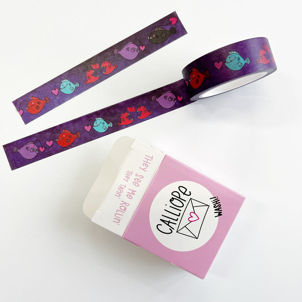 Image of Washi tape with purple background and images of anglerfish  in pink, red, and aqua. 
