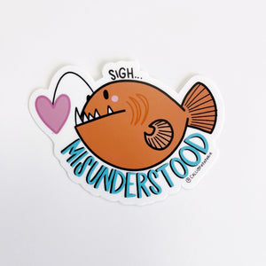 Image of orange anglerfish with pink heart on its fin ray with black and blue text says, "Sigh...misunderstood". 