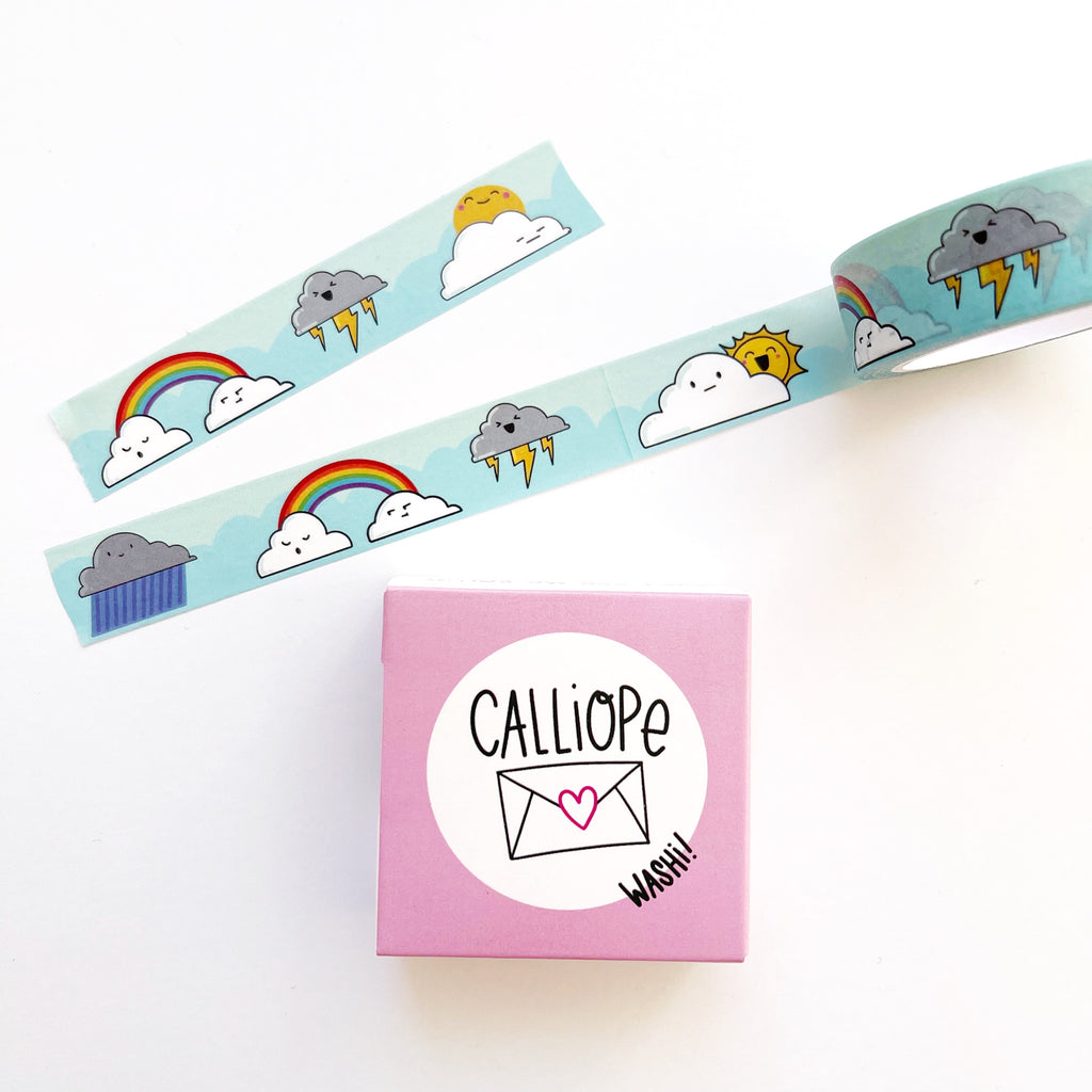 Image of Washi tape with blue background with images of rainbows with clouds, thunder cloud and cloud with sun peeking out. 
