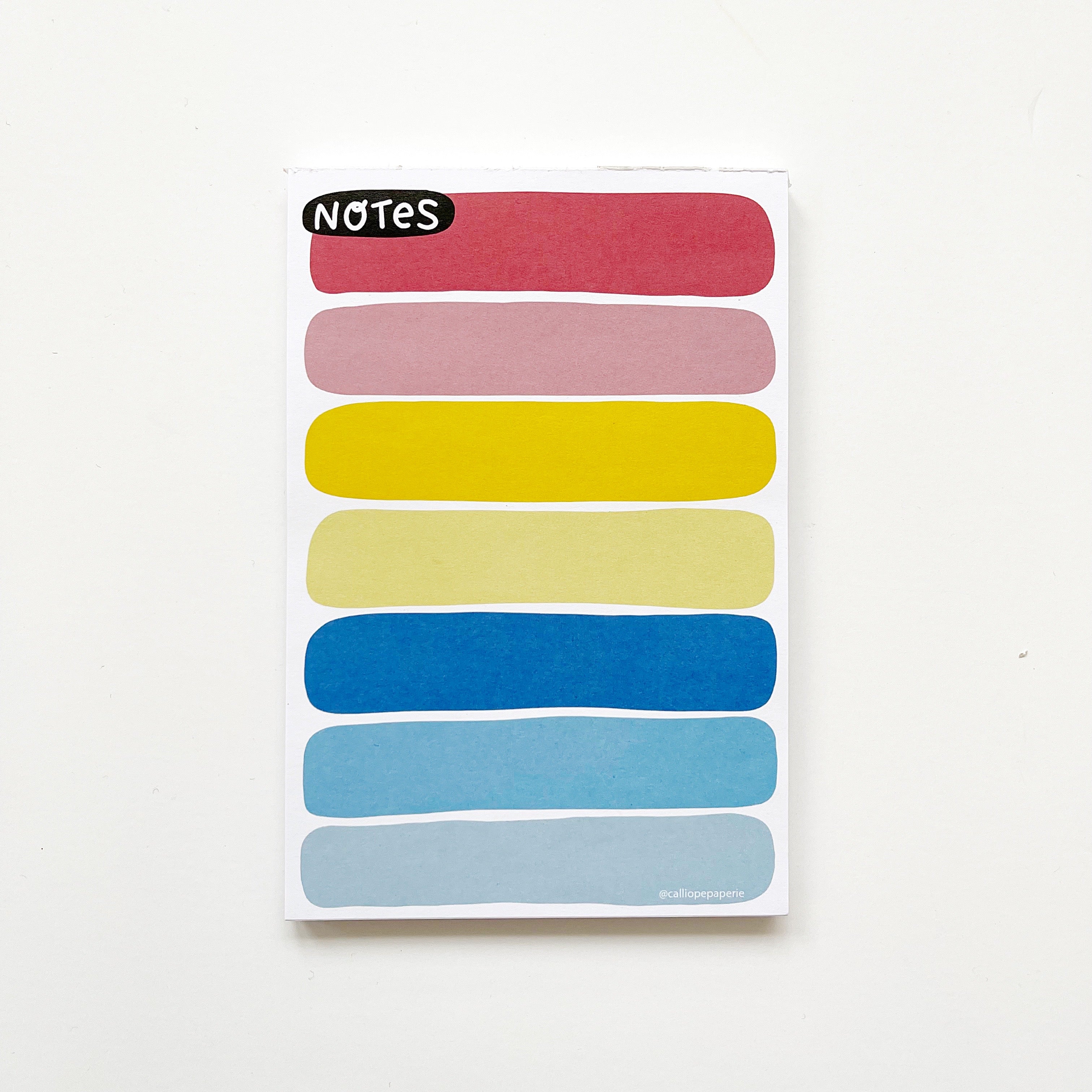 Image of notepad with colored blobs in rainbow colored with black oval with white text says, "Notes". 