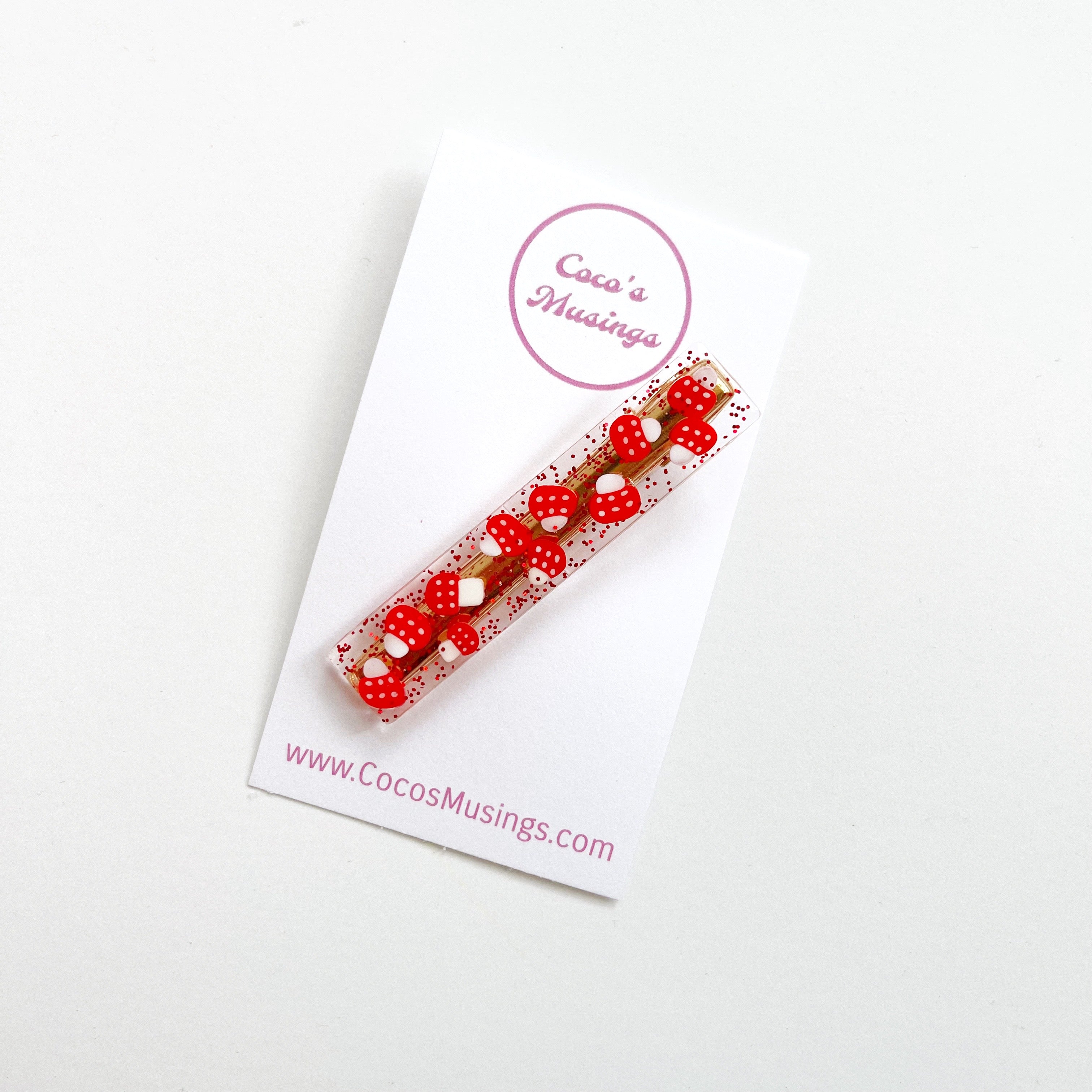 Image of clear clip with red glitter and images of red and white mushrooms rectangular hair clip.  