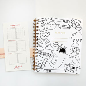 Image of notebook cover with white background and black outlines of shark, cloud, letters, pencil, skull, mailbox, eraser and hot dog.