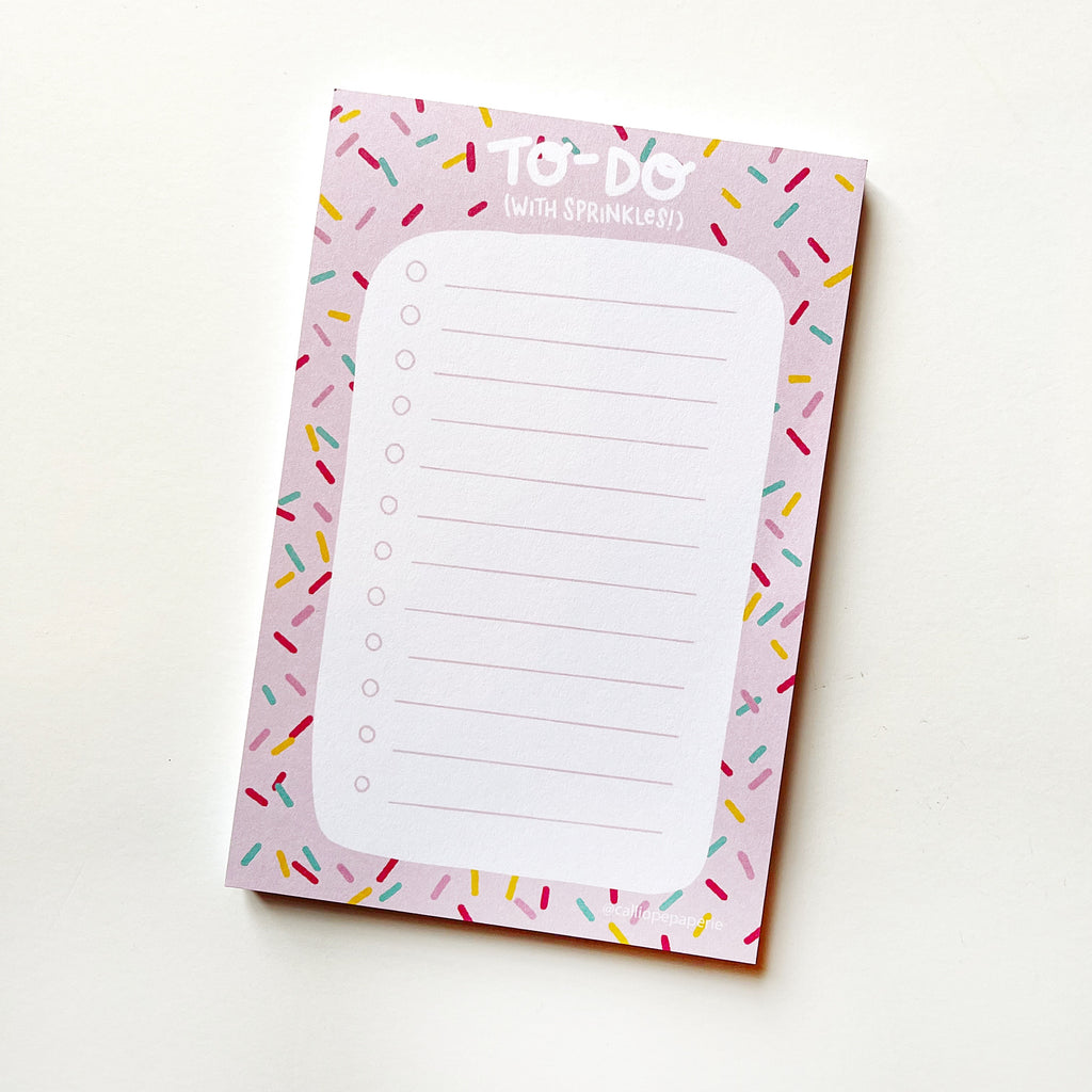 Image of notepad with pink border with multicolored sprinkles and white center with pink lines and checkboxes. White text says, "To-Do with (with sprinkles!). 