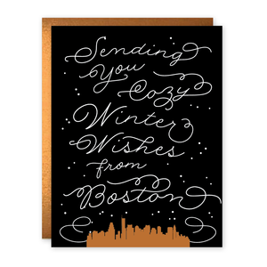 Black background with image of outline of Boston skyline in gold with white text says, “Sending you cozy winter wishes from Boston”. Bronze envelope included. 