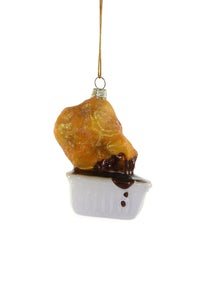 Image of golden chicken nugget dipped in BBQ sauce in white packet. 