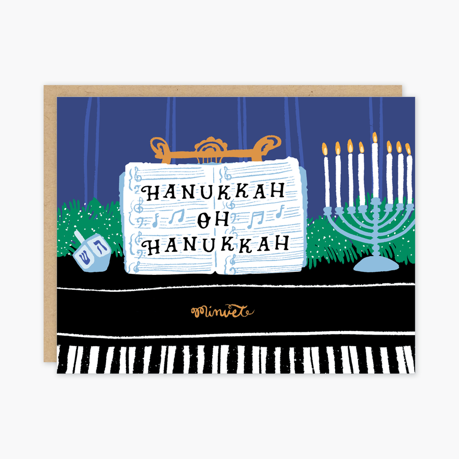 Image of piano with blue background and light blue and white menorah, blue dreidel, and music on music stand with black text says, “Hanukkah oh Hanukkah”. Kraft envelope is included.   