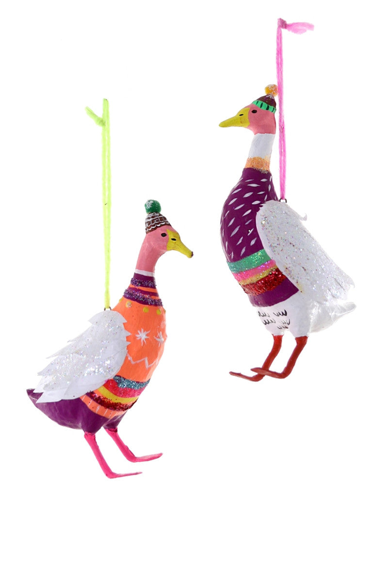 Images of two white ducks wearing festive sweaters and hats with pom poms. 