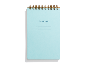 Image of pool blue with letter pressed text says, “Task pad”. “Name” and “Date” with lines for writing. Coiled binding on top.