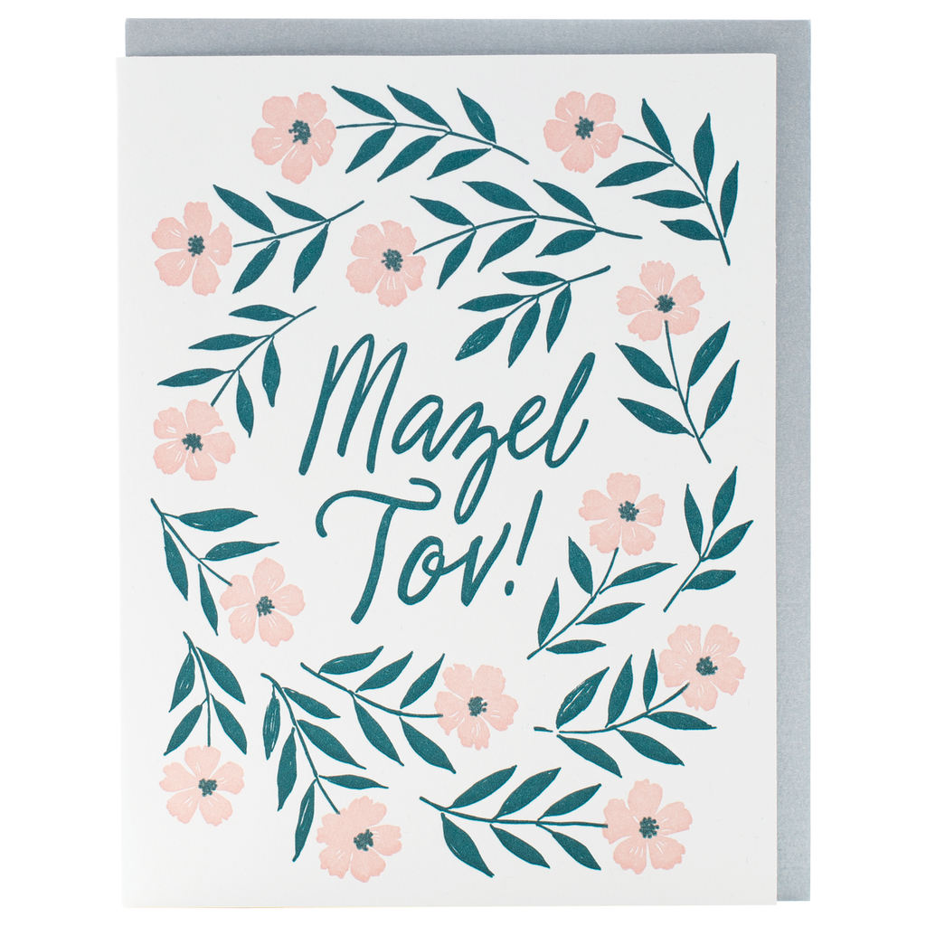 White card with teal text saying, “Mazel Tov!” Images of pink flowers with teal stems circling around text. A gray envelope is included.