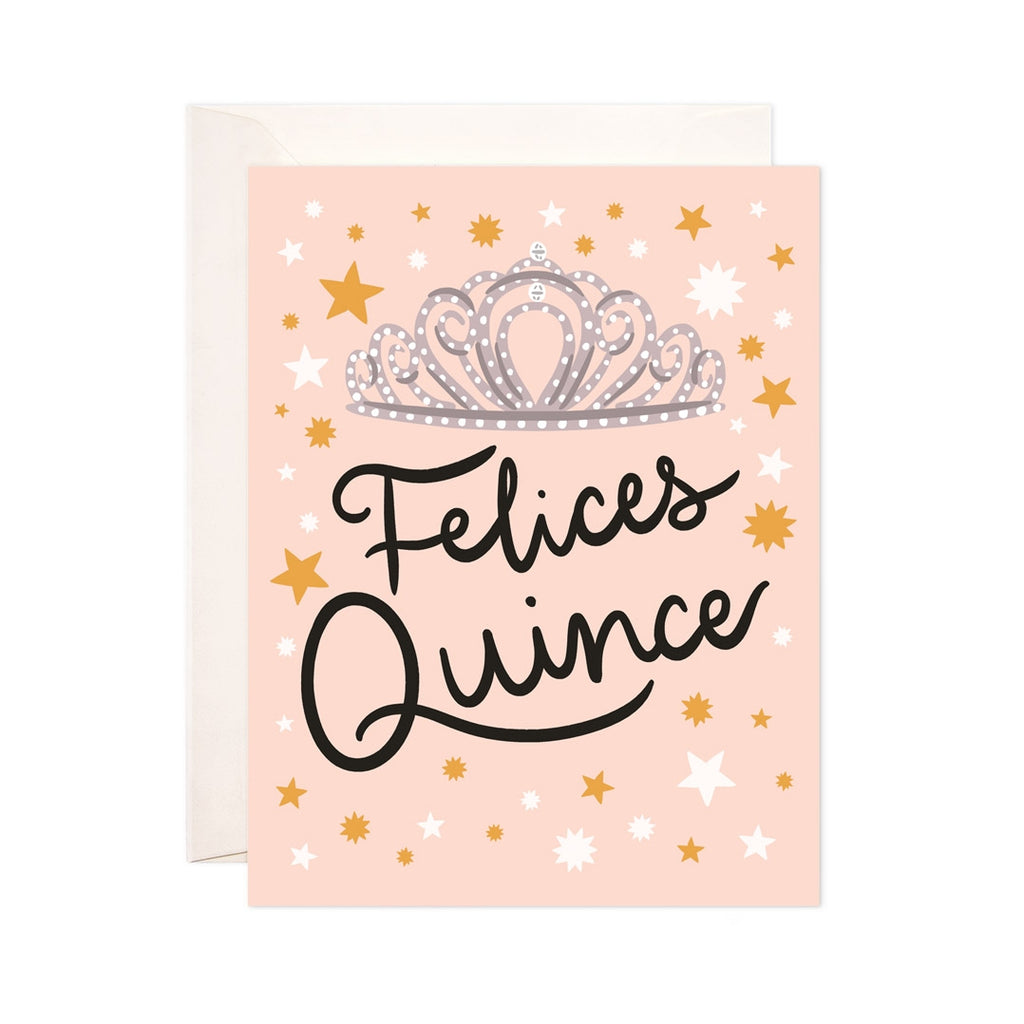 Light pink card with black text saying, "Felices Quince". Images of a jeweled tiara and orange and white stars. An ivory envelope is included.