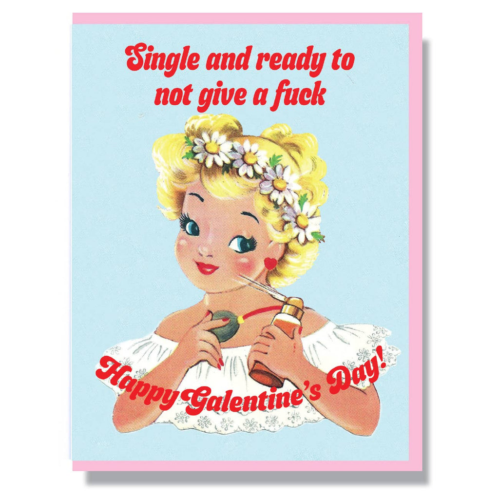 Light blue card with red text saying, “Single and ready to not give a fuck. Happy Galentine’s Day!” Image of a woman with blonde hair wearing a daisy flower crown spraying herself with a perfume bottle. A pink envelope is included.