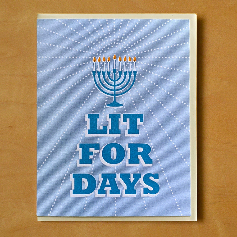 Blue card with blue block letter text saying, "Lit For Days".  Image of a blue menorah with lit candles.  A tan envelope is included.