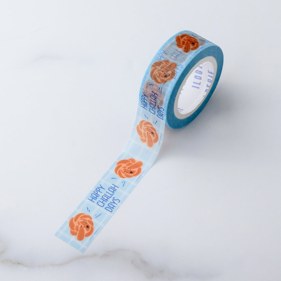 Decorative tape with blue background and blue text saying, “Happy Challah-Days”.  Images of loaves of brown challah bread.