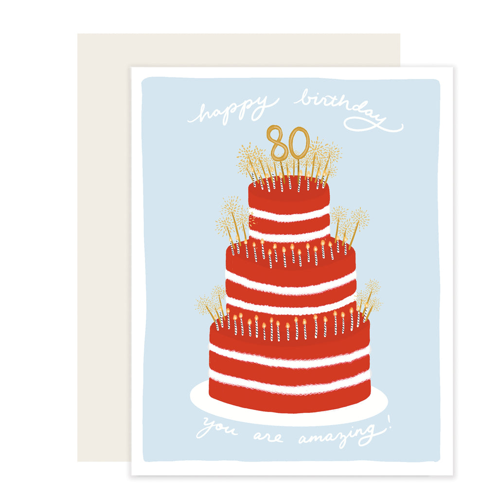 Blue card with white text saying, “Happy Birthday You Are Inspiring”. Images of a three tier red birthday cake with white and gold candles and an 80 gold cake topper. An ivory envelope is included.