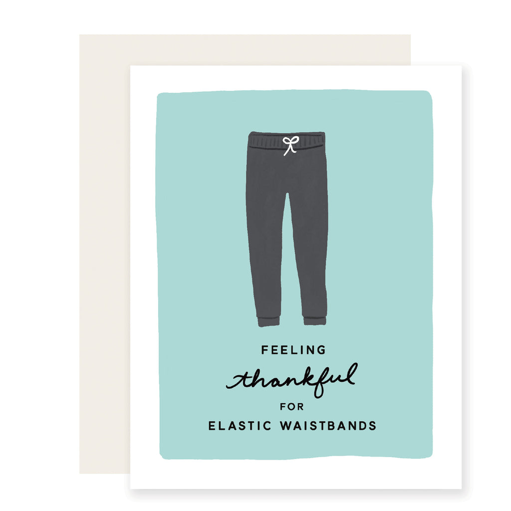 White card with teal inset background with black text saying, “Feeling Thankful for Elastic Waistbands”. Image of a pair of gray sweatpants. An ivory envelope is included.