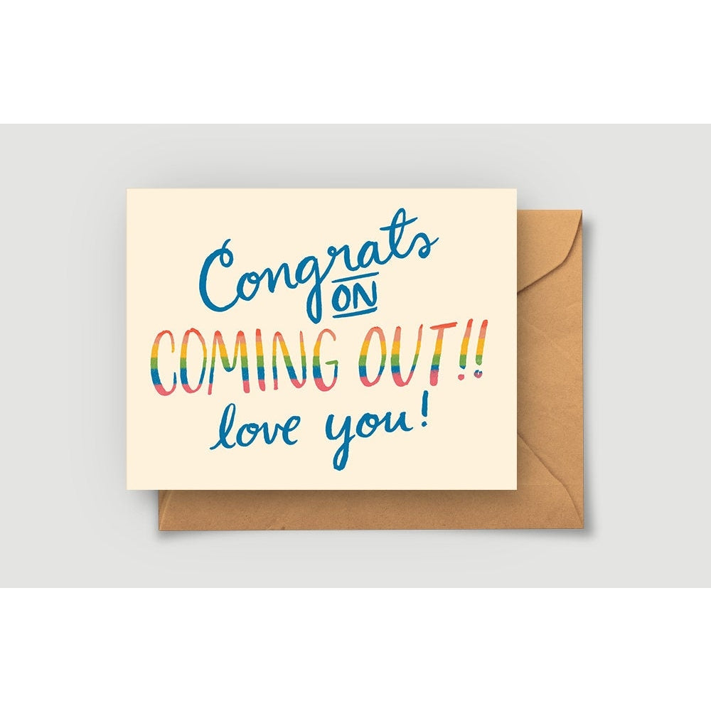 Ivory card with blue text saying, “Congrats on Coming Out!! Love You!” “Coming Out” wording is in rainbow colored text. A tan envelope is included.