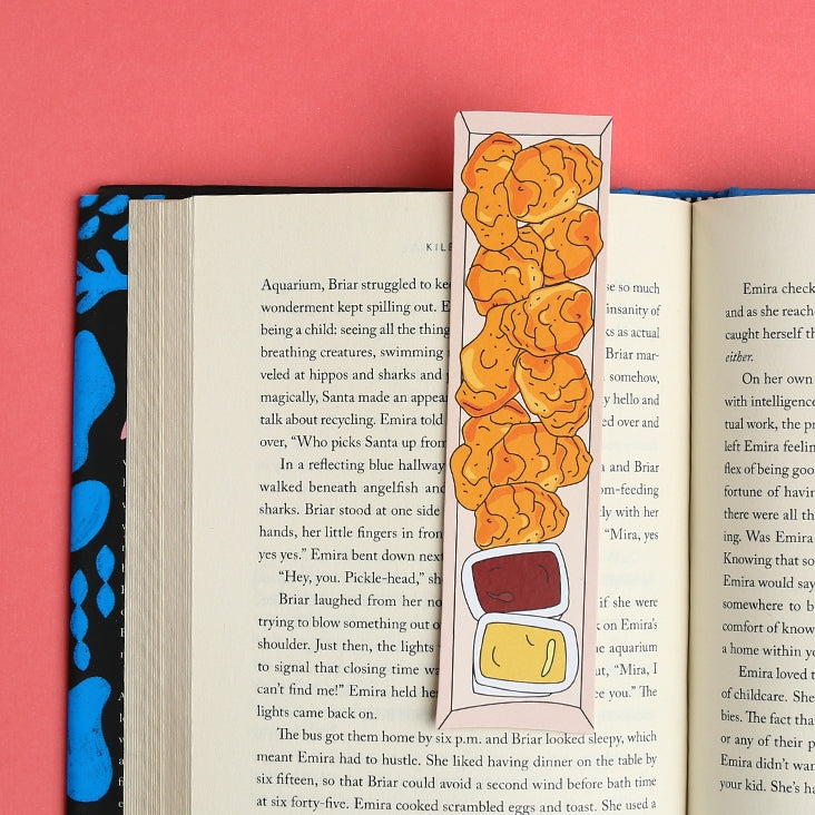 Image of opened book with bookmark shaped like a box of golden chicken nuggets with honey mustard and BBQ sauce. 