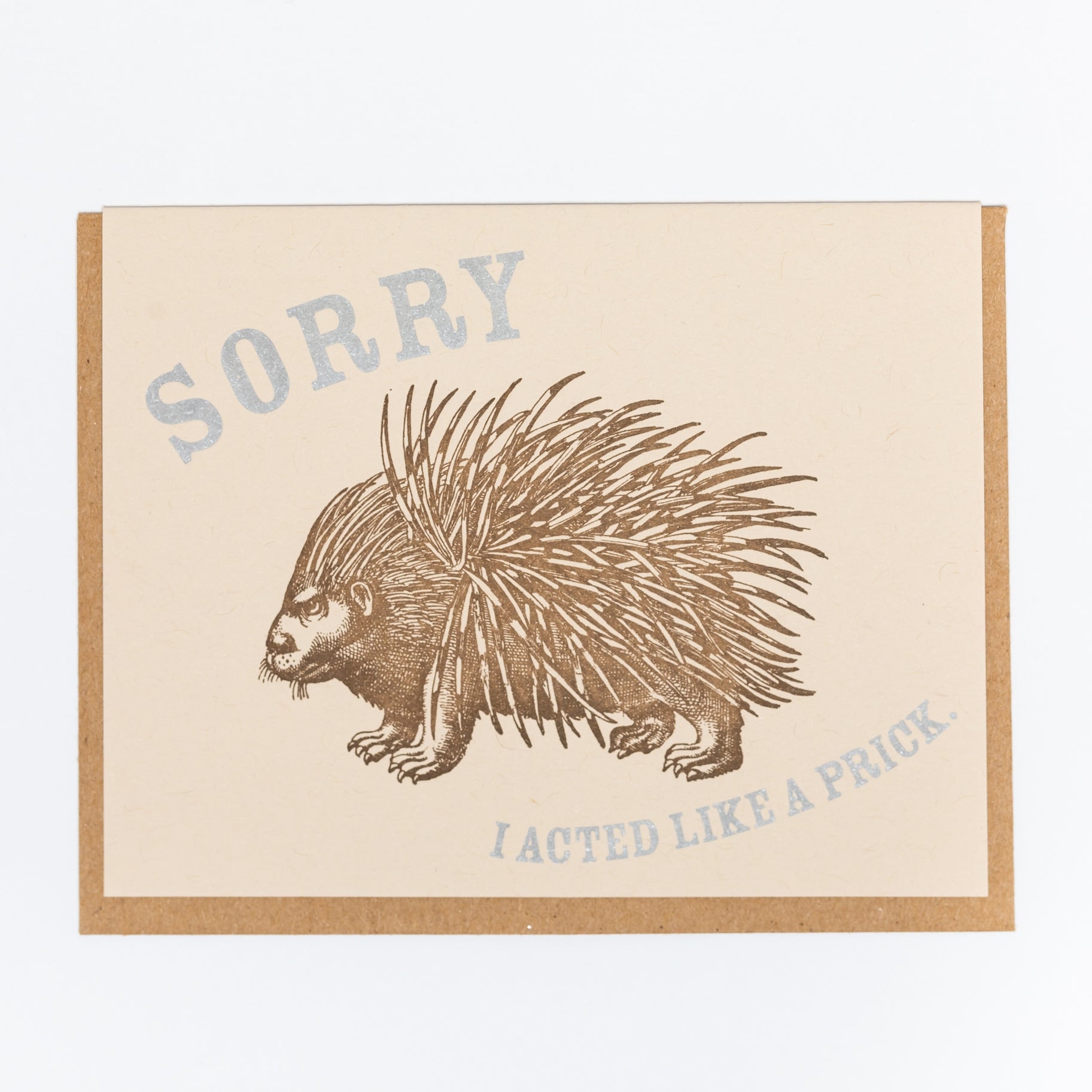 Tan card with light blue text saying, "Sorry I Acted Like a Prick". Image of an angry brown porupine in center of card.  A brown envelope is included.