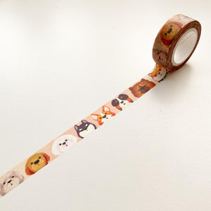 Peach tape with various dog faces in a repeating pattern. Dog faces included white fluffy dog, brown dogs, gray dogs and black dogs.