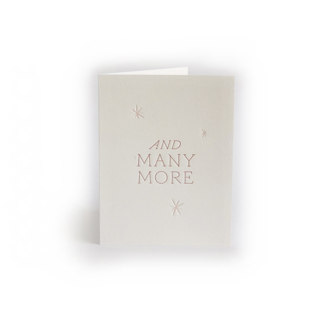 Gray card with silver text saying, “And Many More”. Images of snowflakes. An envelope is included.