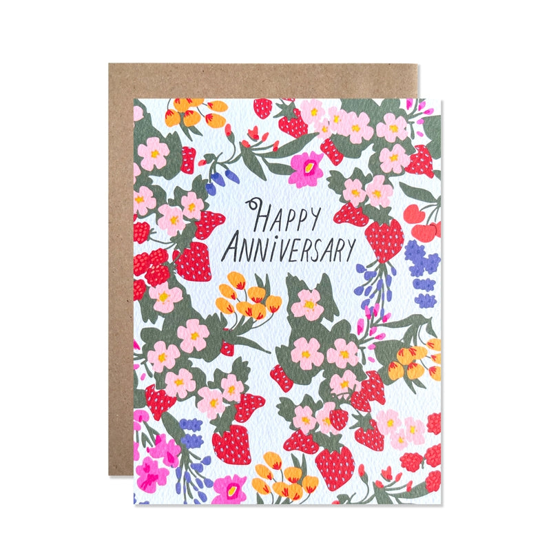 White card with black text saying, “Happy Anniversary”. Images of multi colored flowers and red strawberries. A brown envelope is included.