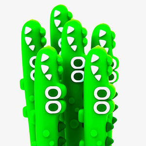 Image of six bright green crocodile pens with white detail around eyes and white teeth. 