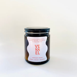 Image of brown glass jar with black lid and ivory label with red text says, “Vessel” and “Harvest Moon”. 
