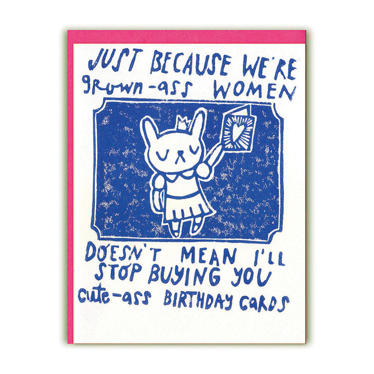 White card with blue text saying, “Just Because We’re Grown-Ass Women Doesn’t Mean I’ll Stop Buying You Cute-Ass Birthday Cards”. Image of a white female dog wearing a dress holding up a birthday card set on a blue background. A pink envelope is included.