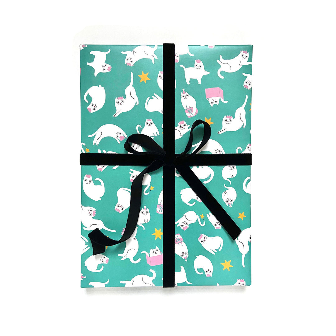 Image of gift wrapped in aqua background paper with images of white cats in various poses with pink accents and yellow stars in background.    