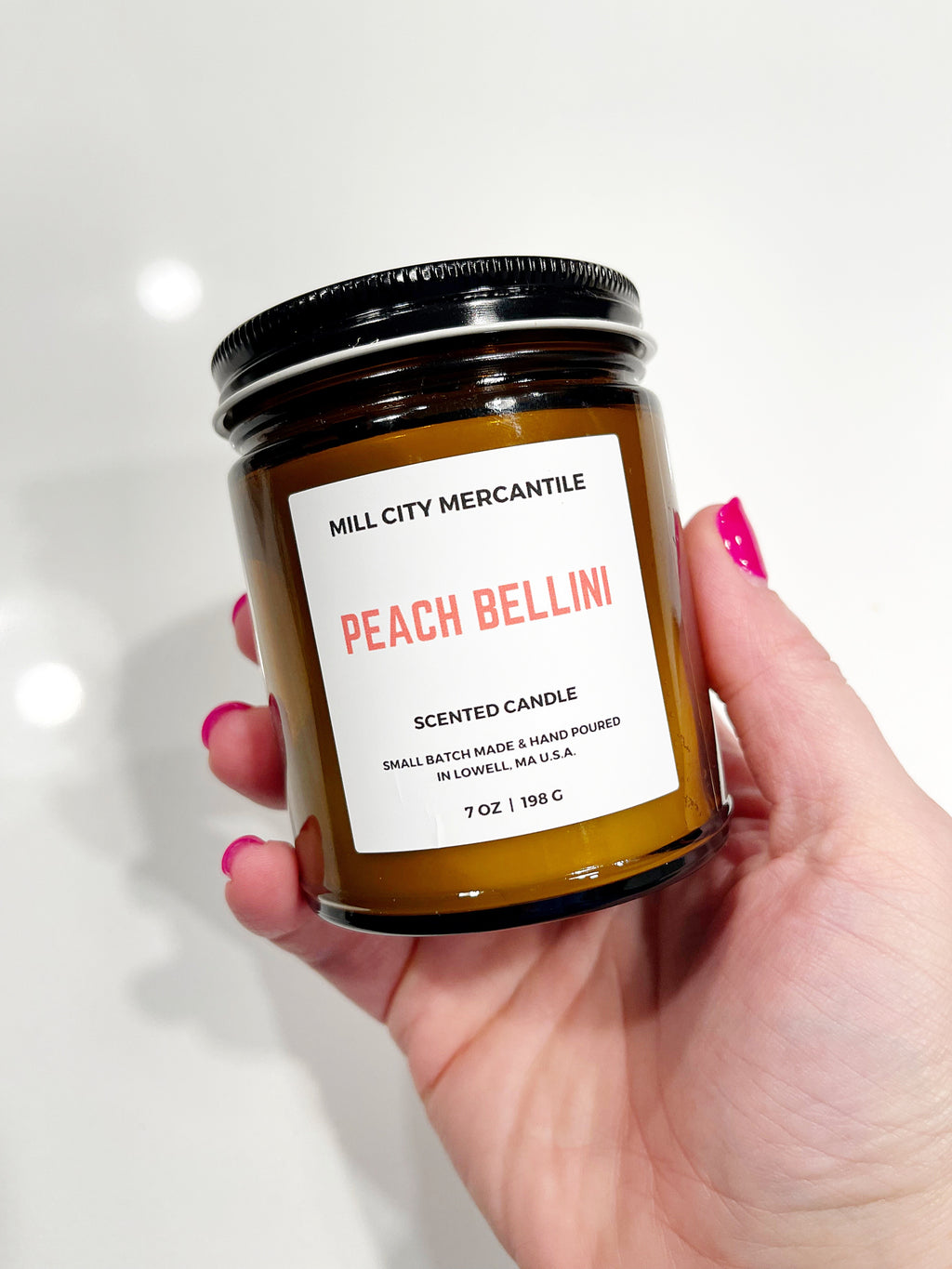 Image of brown glass jar with black cap. Ivory label with black text says, “Mill City Mercantile”.  Peach text says, “Peach Bellini”.   