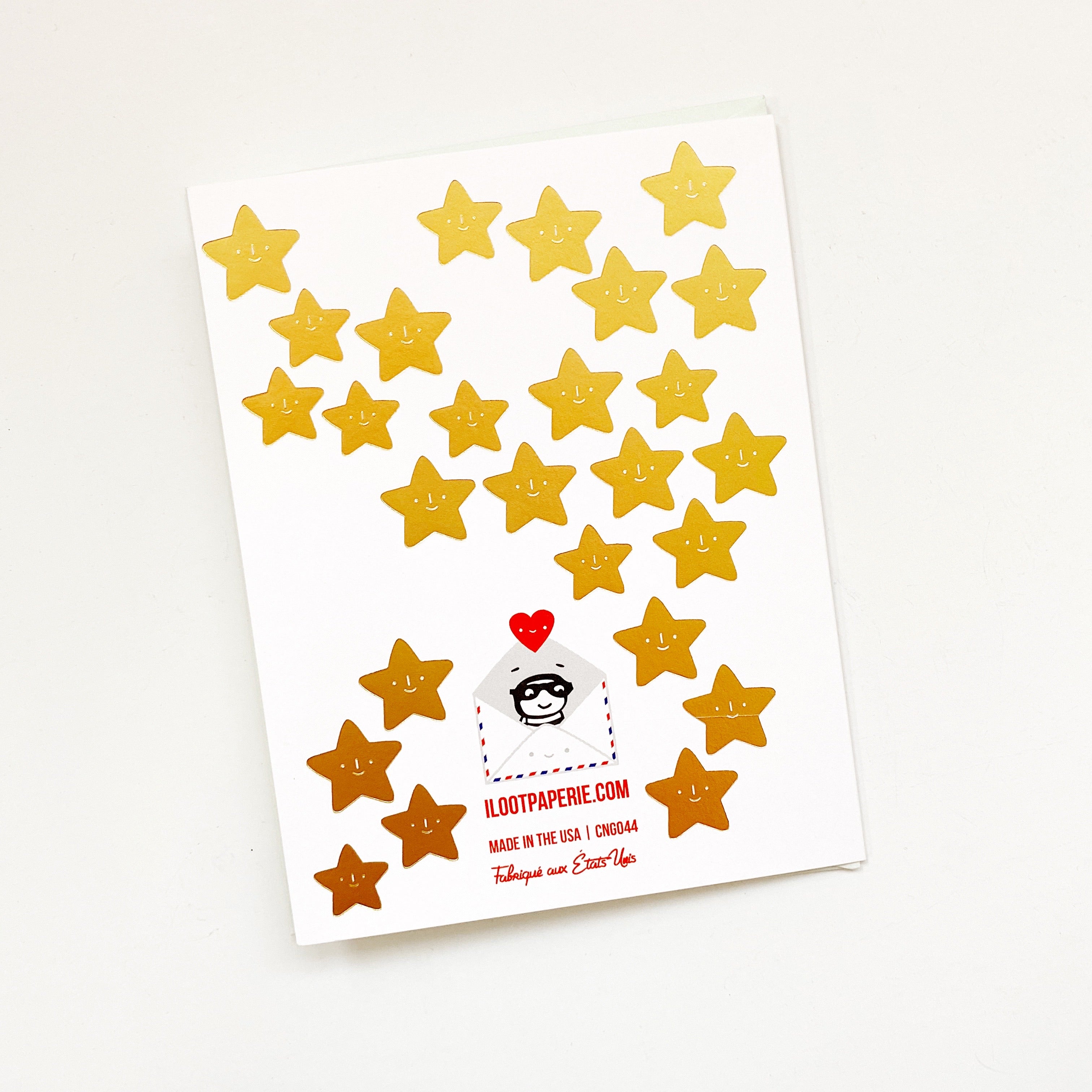 White card with several gold foil stars scattered on back of card. An envelope is included.
