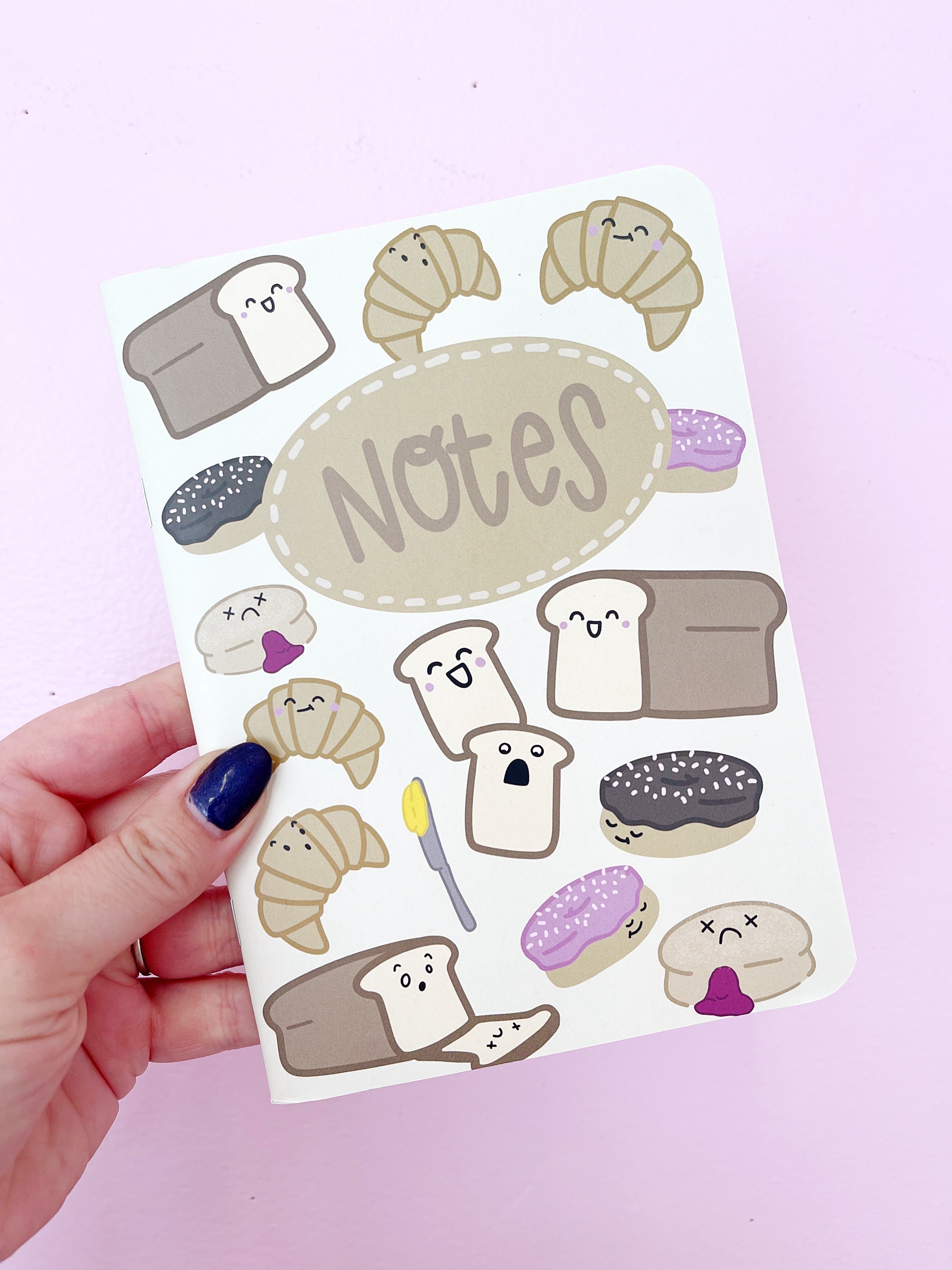 Image of notebook cover with cream background and images of bread, croissants, donuts and slices of bread with tan text says, "Notes". 