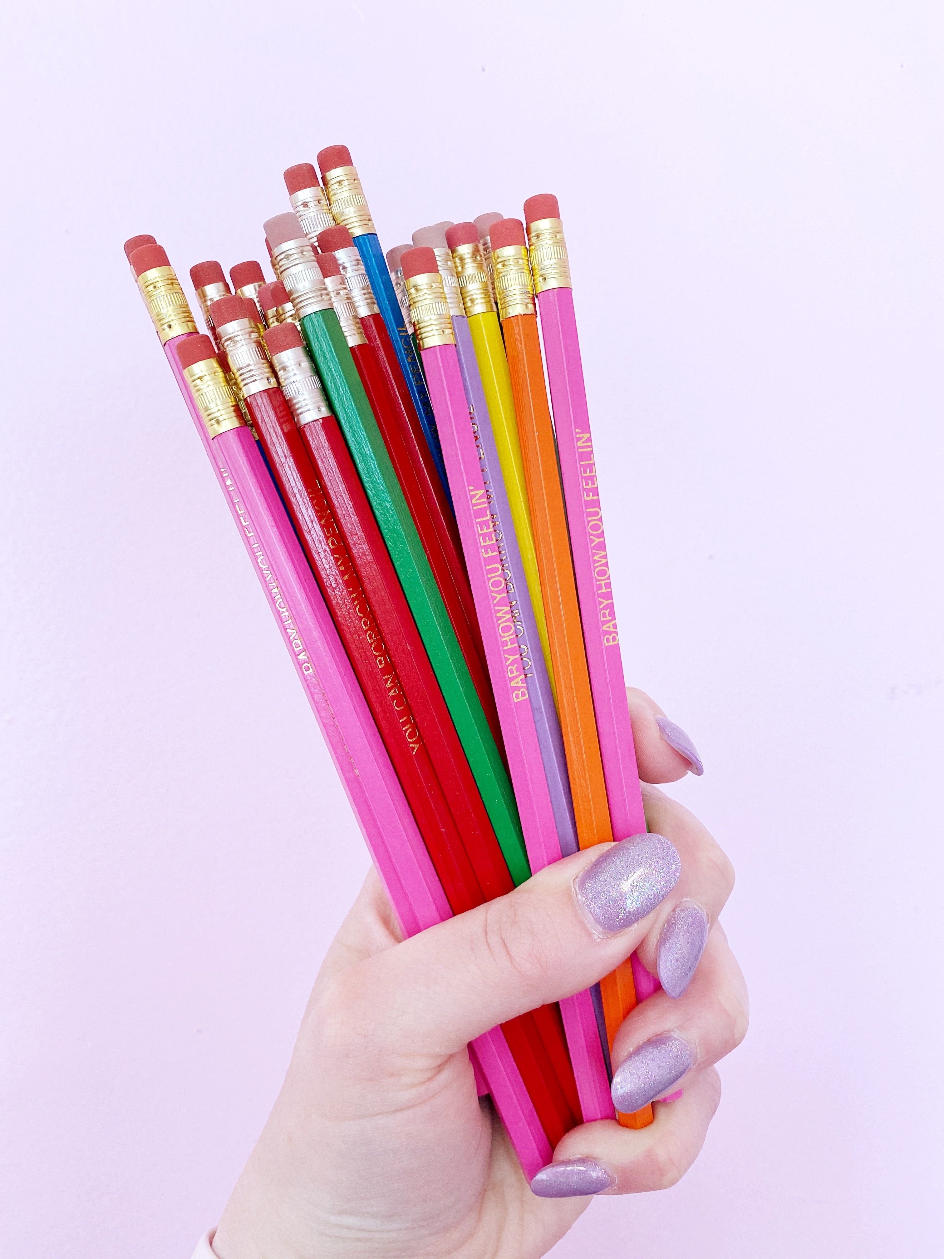 Image of a hand holding a bouquet of pencils in many colors. 