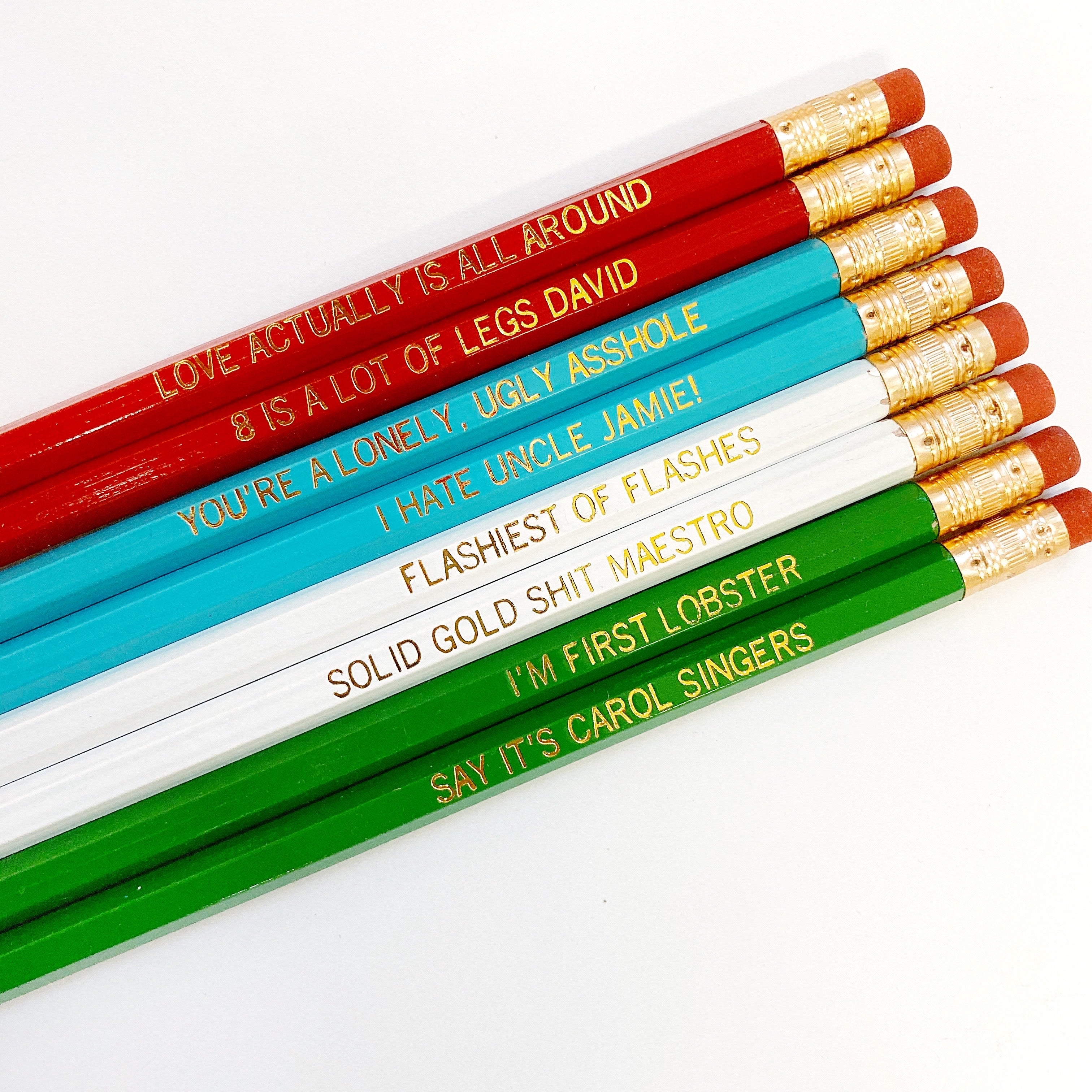 Eight pencils with gold text says, "Love Actually Is All Around, 8 Is A Lot Of Legs David, You're A Lonely, Ugly Asshole, I Hate Uncle Jamie! The ,Flashiest Of Flashes ,Solid Gold Shit Maestro!, I'm First Lobster,Say It's Carol Singers". 