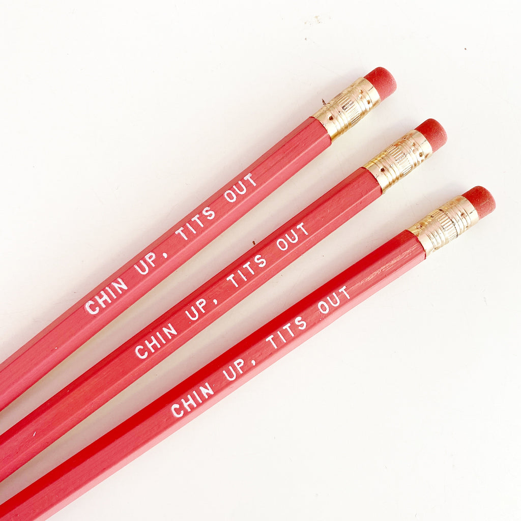 Pink pencils with white text says, "Chin up, tits out".