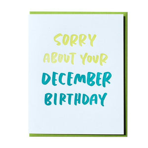 Light blue card with geen and blue text saying, "Sorry About Your December Birthday". A green envelope is included.